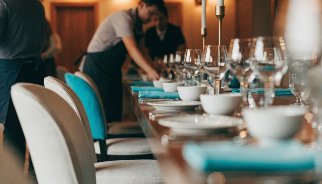 Mesa longa montada para um grupo ou evento privado em restaurante, equipe organizando o salão